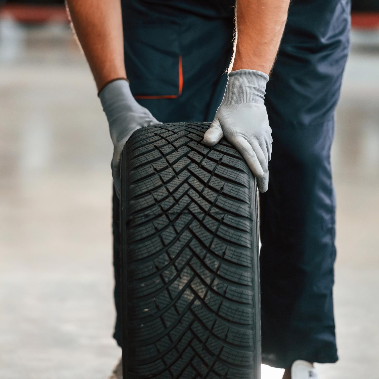 Tyre fitter carrying a new car tyre in the Farnborough workshop